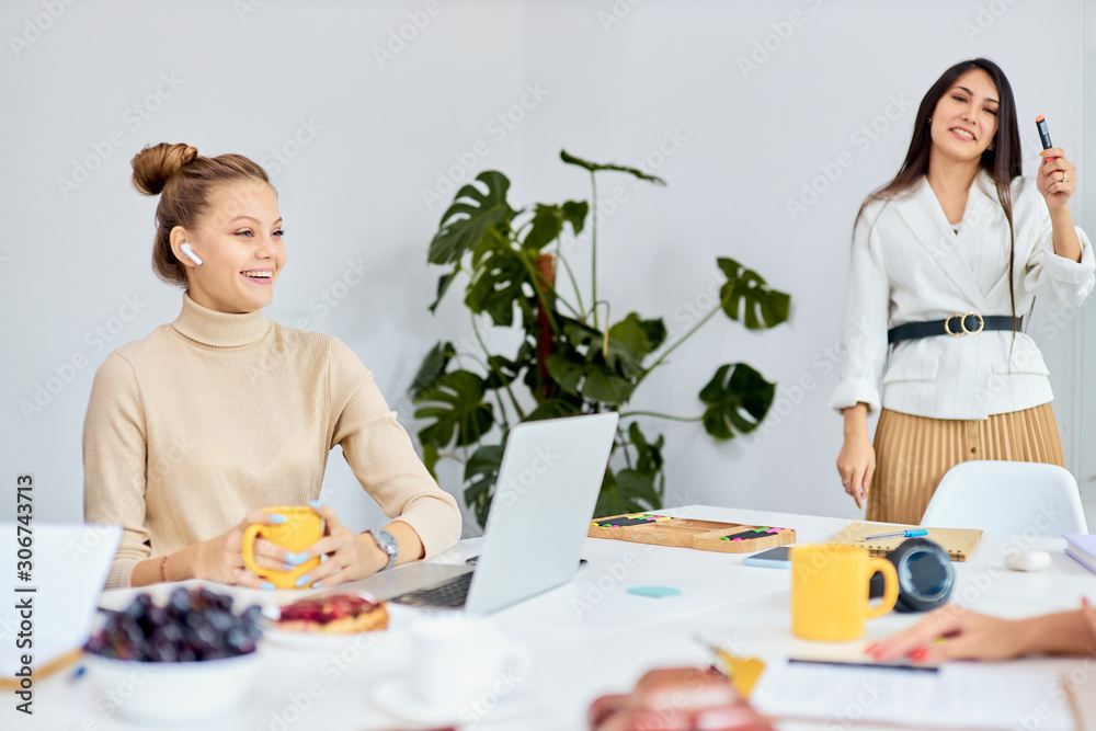 Young beautiful business coach teacher team leader represent her business strategy to co-workers in white office, multi-ethnic group of listeners Young beautiful business coach teacher team leader represent her business strategy to co-workers in white office, multi-ethnic group of listeners