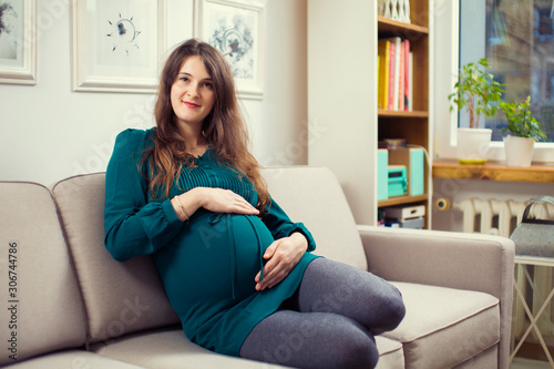 Pregnant woman on a couch in living room. pregnancy photo of a young woman. Vintage room and couch. 