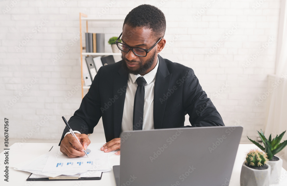 Serious young manager working with documents in his office Serious young manager working with documents in his office