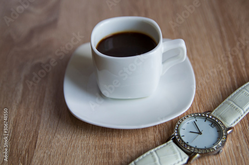 A Cup of coffee in the morning. Wrist watch. Warm tone. Good morning.