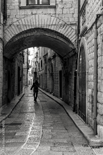 uomo caminando su vecchia strada di pietra sotto un arco
