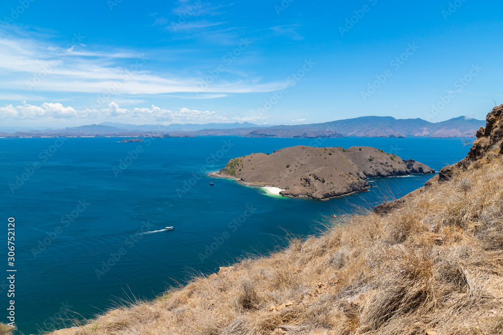 Tropical sea and small islands around Komodo National Park with hills, blue sea water and blue sky. Indonesia