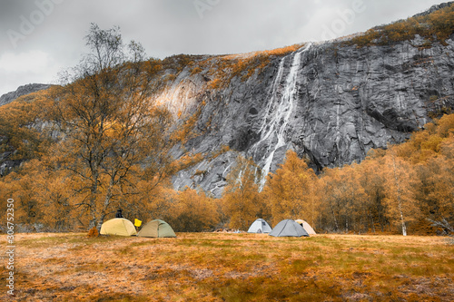 tourist tents under the Manafossen Falls in the valley of the river Man in Norway in fall photo