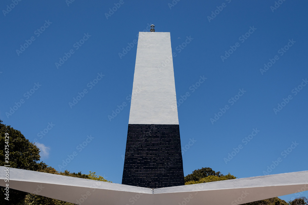 Black and white lighthouse against blue sky