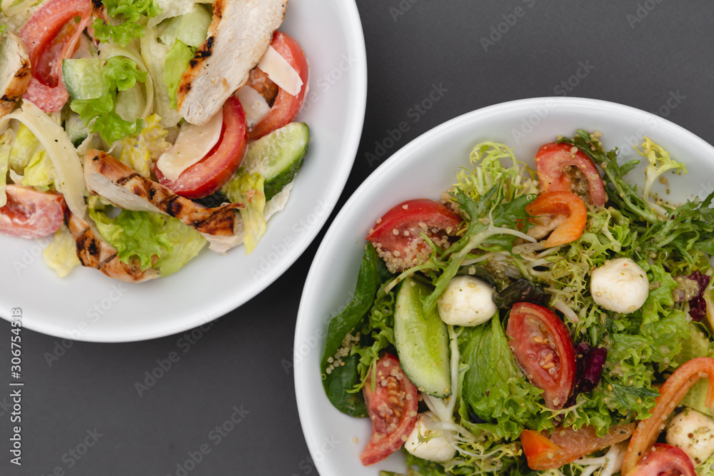 white deep plates with fresh salad ingredients mixed with sauce placed on an attractive background. A place for a menu, banner or advertisement