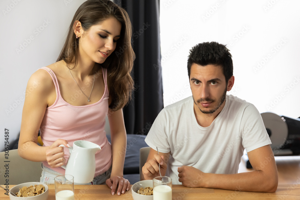 Young beautiful couple eats breakfast cereal with berries and milk. Young beautiful couple eats breakfast cereal with berries and milk.