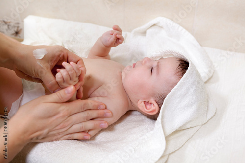 Mother carefully applying medical ointment on baby dry skin after bathing