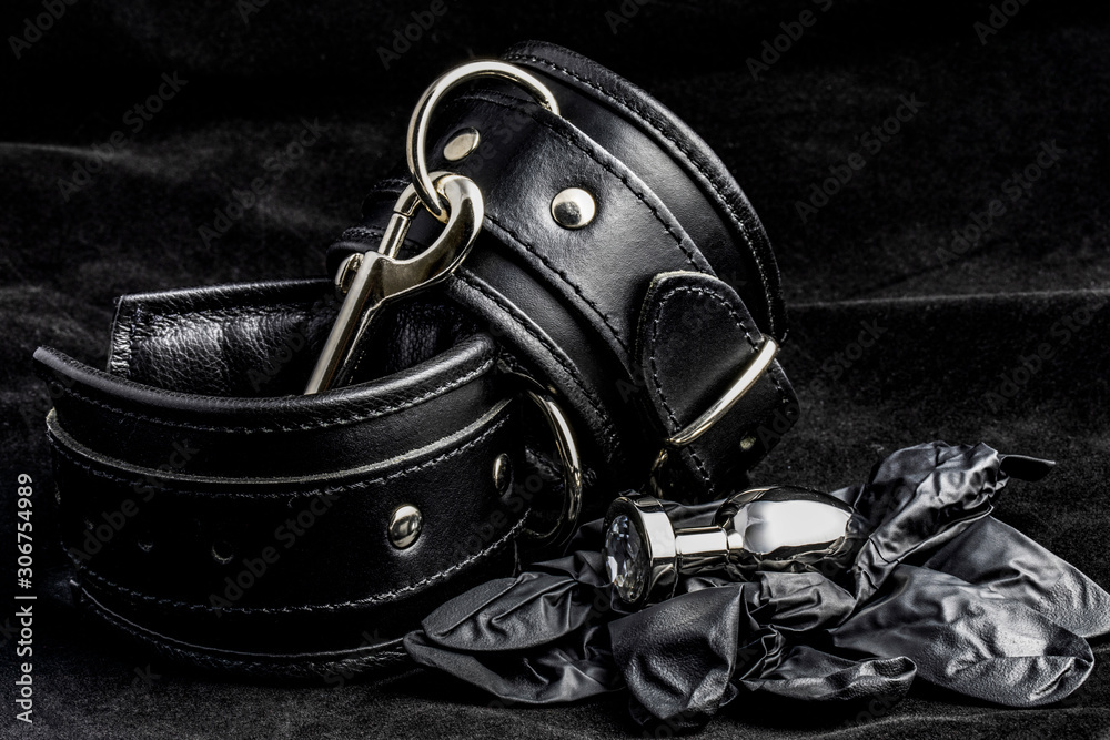 Leather handcuffs, anal plug, latex gloves on black background. Leather handcuffs, anal plug, latex gloves on black background.