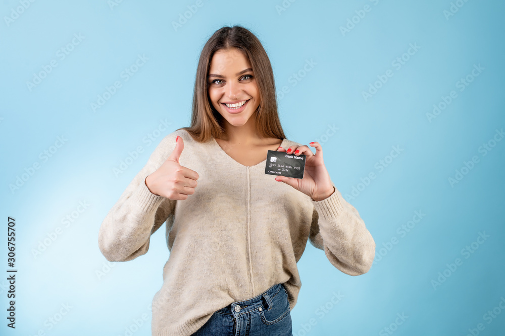 cheerful woman holding credit card and showing thumbs up isolated over blue cheerful woman holding credit card and showing thumbs up isolated over blue