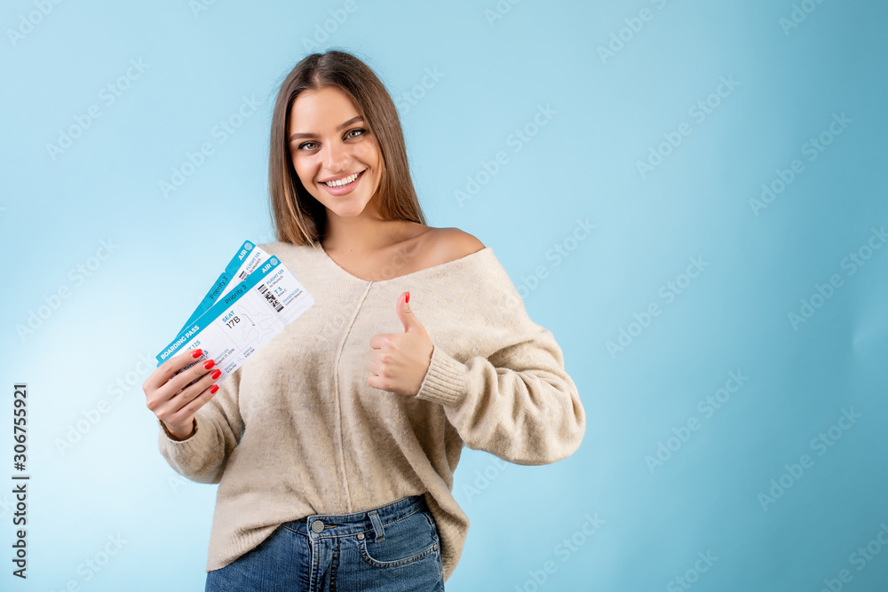 woman with boarding pass plane tickets showing thumbs up and smiling isolated over blue woman with boarding pass plane tickets showing thumbs up and smiling isolated over blue