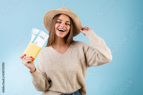 beautiful woman with boarding pass plane tickets in passport and tourist hat isolated over blue