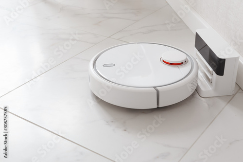 Robot vacuum cleaner on charging. Room with white ceramic tile and walls