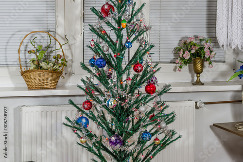 traditional Christmas tree decorated with various decorations and lights zoom on full frame on the background of a white window