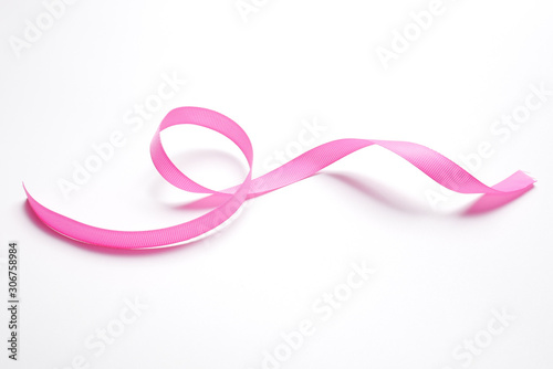Pink ribbon on a white background. Abstract wavy ribbon shape. © Kryuchka Yaroslav