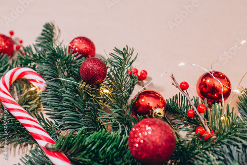 craft background with christmas tree and balls closeup. Free space for text. Red Christmas balls, branches of spruce, candy in the form of sticks. Christmas background
