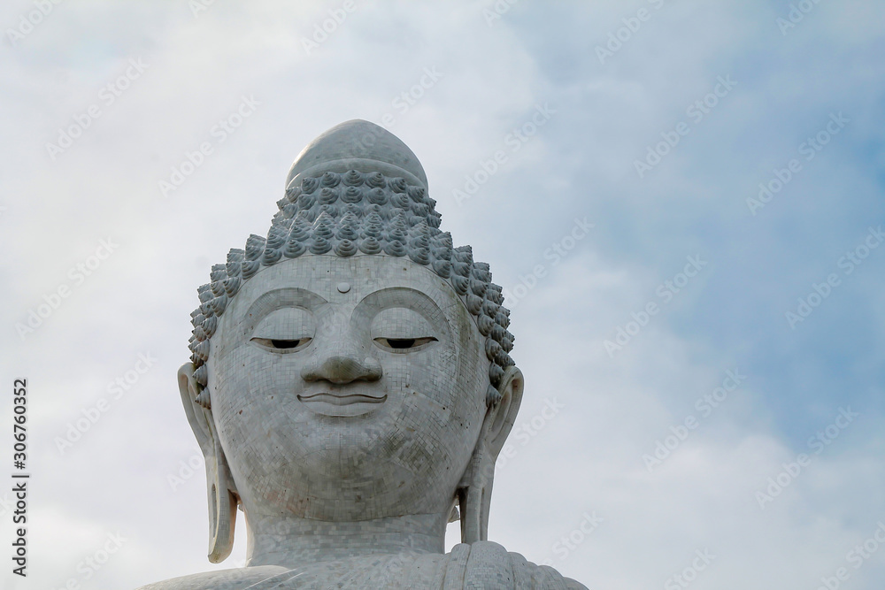 Close-up marble statue of a snow-white Big Buddha on the island of Phuket in Thailand. A giant Buddha figure made of marble bricks on Mount Nakaked in honor of the King of Thailand.