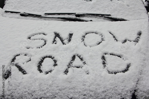 SNOW ROAD written word Inscription on snowy car bonnet with wiper blades close up, winter snowfall in Europe photo