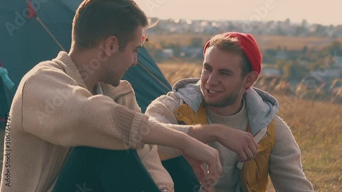 lovely young gay couple spends time together in tourist camp on meadow in early autumn morning slow motion closeup