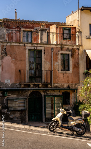 view on an old building with a scooter in front in from taormina, sicily island, italy