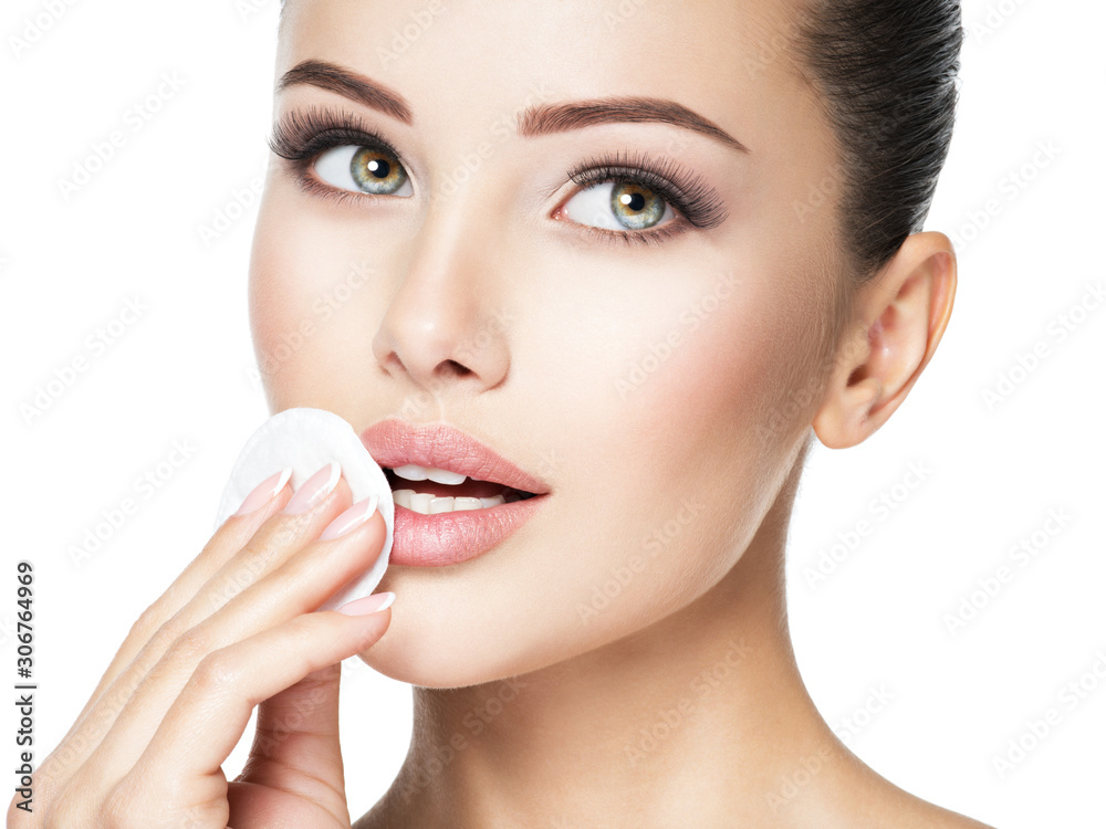 Beautiful woman cleans the face with  cotton swab.