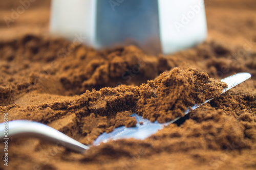 Scattered on the table ground coffee and a metal Turk with a spatula close up soft focus