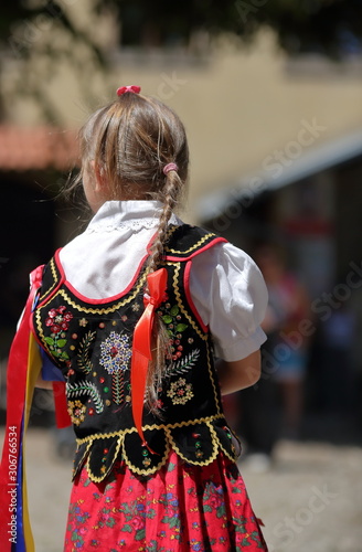 Little Polish girl in traditional folk costume stands on her back