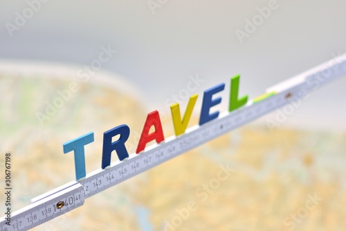 La palabra travel, hecha con letras de madera sobre un metro de carpintero blanco