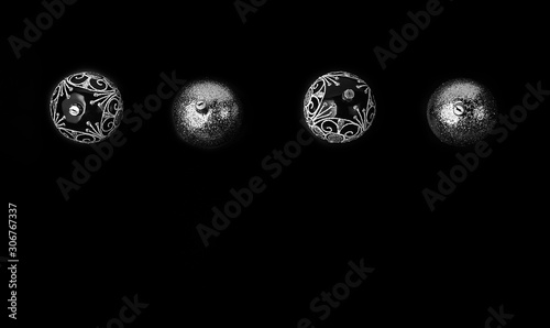 Trendy Christmas silver and black balls decor on isolated black background. Christmas backdrop for your design. Flat lay style.