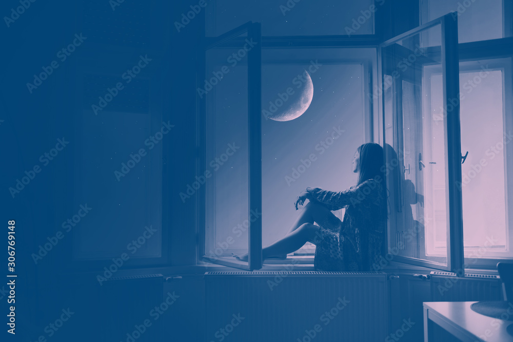 Woman sitting at the window looking at stars and the moon, Artistic Photography