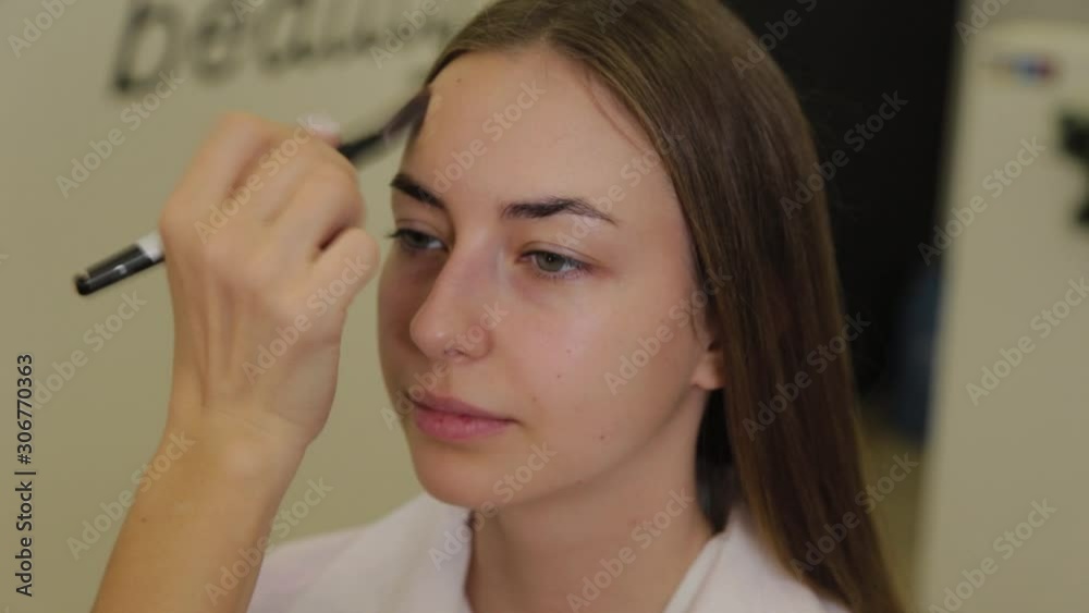 Professional make-up artist applies foundation cream on client's face with brush. Professional make-up artist applies foundation cream on client's face with brush.