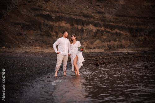 Male groom and female bride standing in the sea on the beach