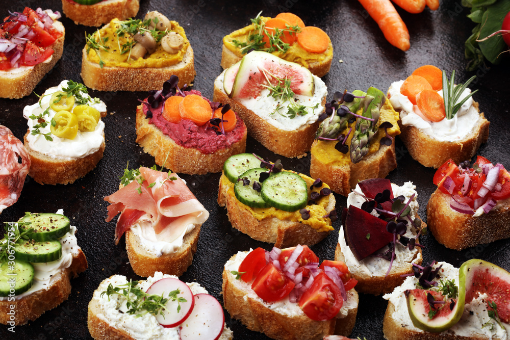 Assorted bruschetta with various toppings. Appetizing bruschetta or brie crostini. Variety of small sandwiches. Mix bruschetta on table Assorted bruschetta with various toppings. Appetizing bruschetta or brie crostini. Variety of small sandwiches. Mix bruschetta on table