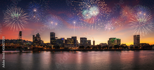 Flashing fireworks on a dramatic sunset sky with Portland, OR cityscape with Willamette river and Hawthorne bridge