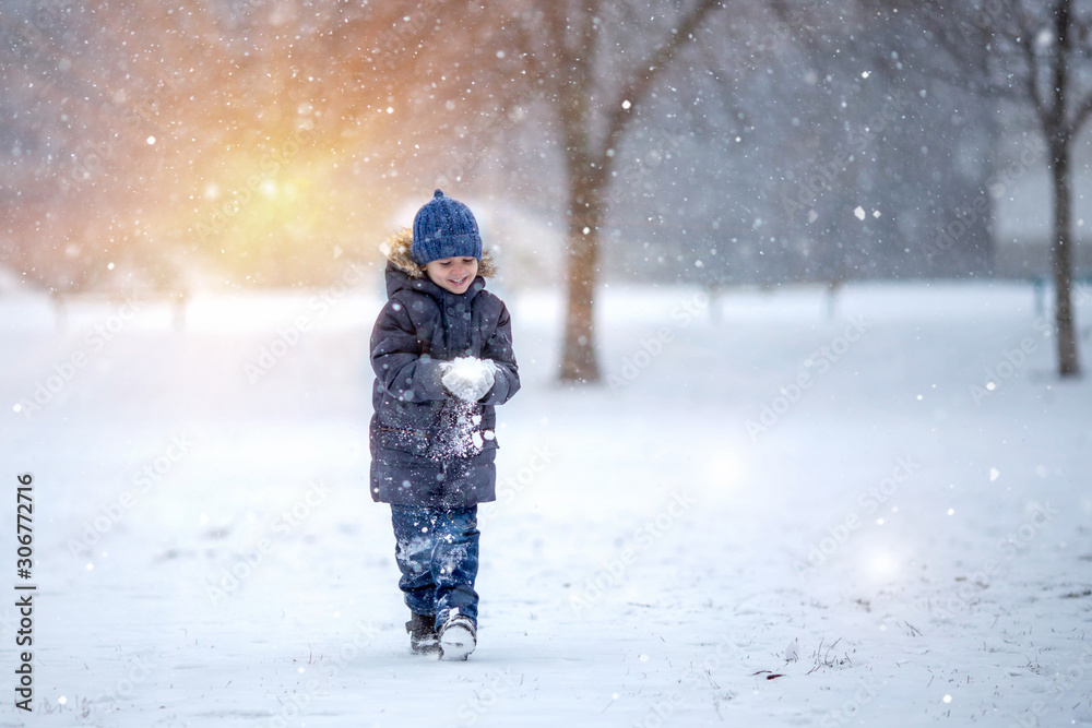 A little boy in a hat and jacket laughs and rejoices in the winter snow . A little boy in a hat and jacket laughs and rejoices in the winter snow .