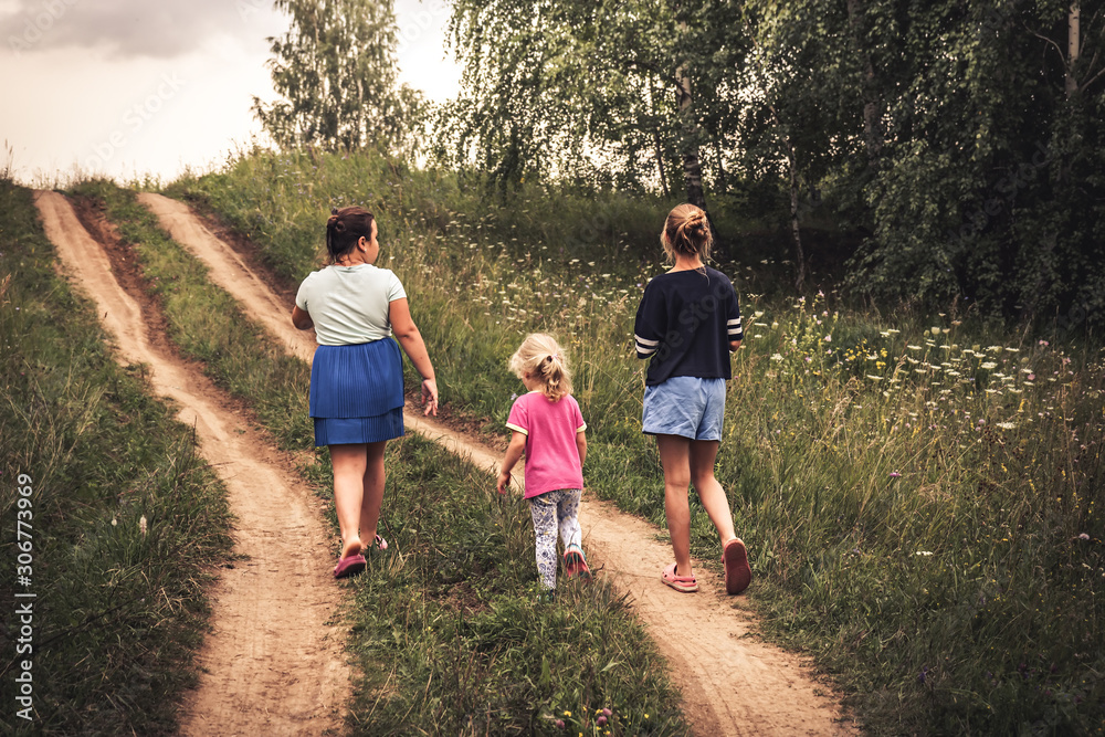 Children walking on rural road uphill towards dramatic sky on horizon in countryside  concept happy childhood lifestyle