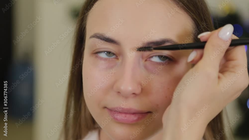 Professional makeup artist paints eyebrows to a client of a beauty salon. Professional makeup artist paints eyebrows to a client of a beauty salon.
