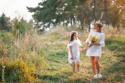 Mother and daughter having fun in the park. Happiness and harmony in family life. Beauty nature scene with family outdoor lifestyle. Mother's Day