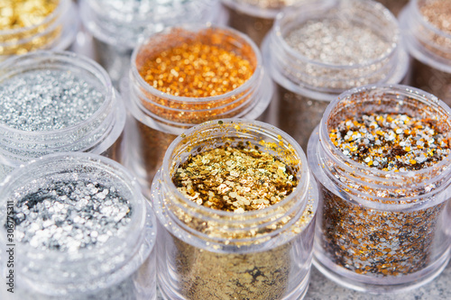 Beautiful glitter close up in golden and silver tones in small glass jars, selective focus