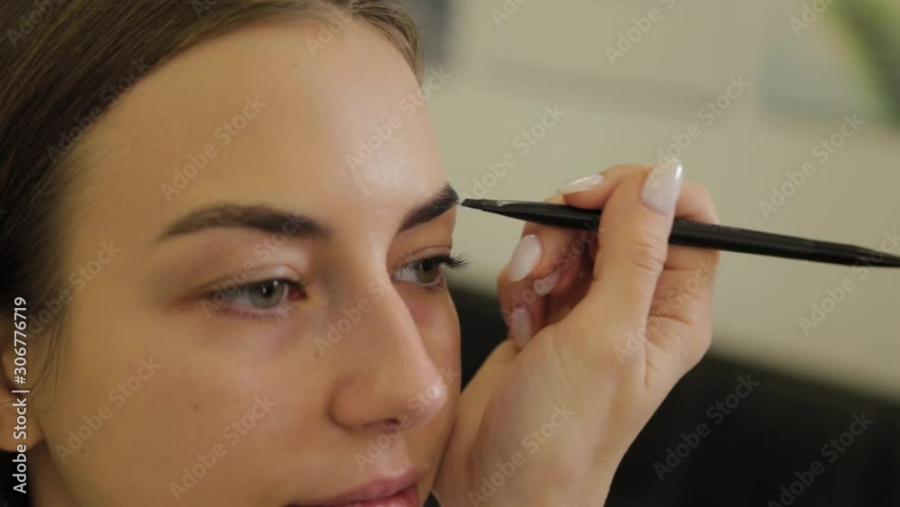Professional makeup artist paints eyebrows to a client of a beauty salon. Professional makeup artist paints eyebrows to a client of a beauty salon.