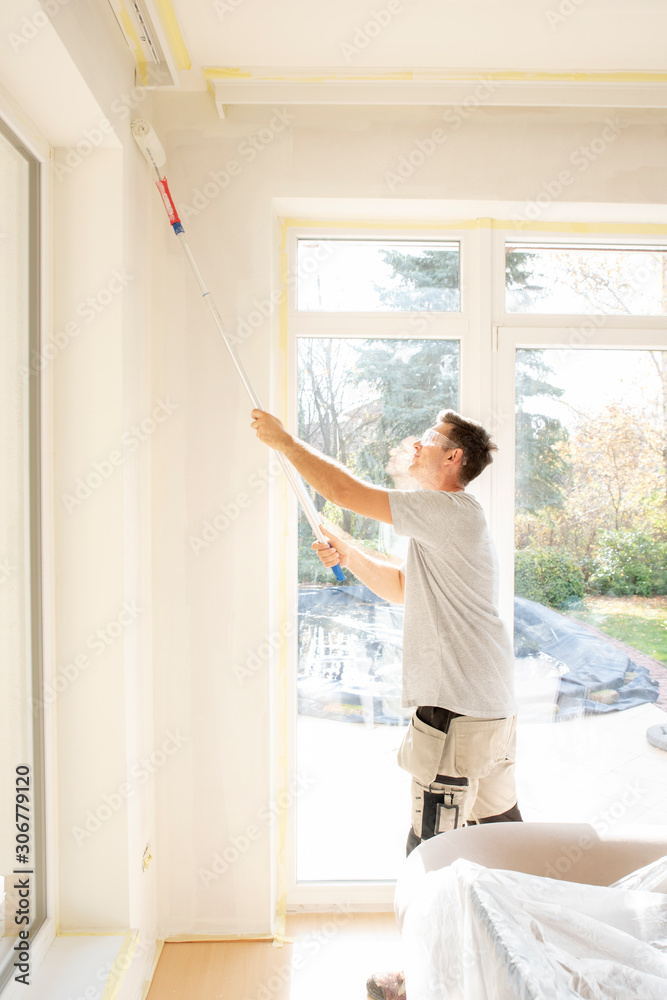 Young man painting the wall in the house Young man painting the wall in the house