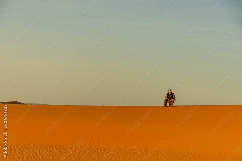 Man sitting in the Sahara desert in Merzouga. Morocco