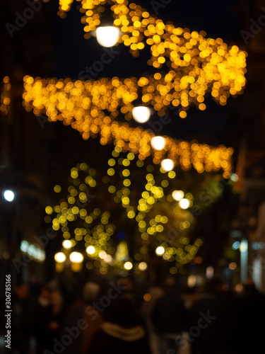 defocused people walking on a street with christmas lighting - blurred background