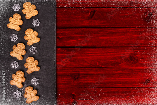 Gingerbread cookies and snowflakes in decoration on red wooden table, directly above.