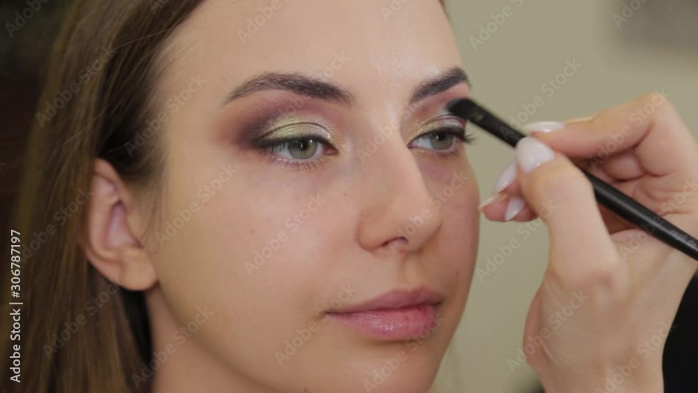 Professional makeup artist puts eye shadow on a client of a beauty salon. Professional makeup artist puts eye shadow on a client of a beauty salon.