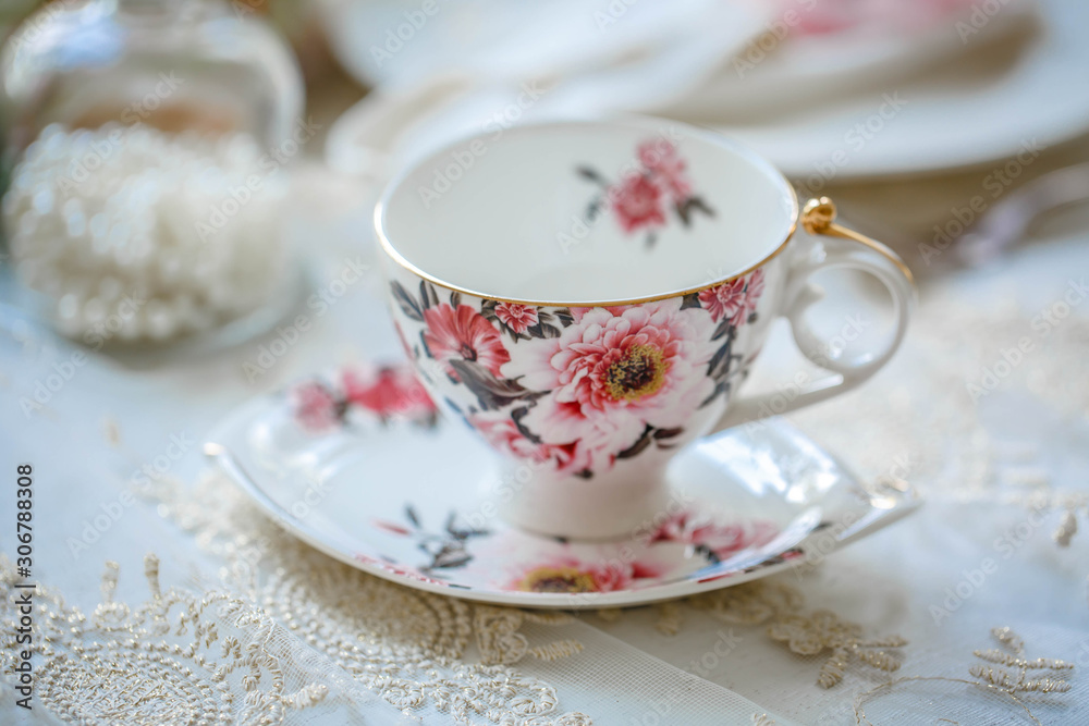 Luxury porcelain tea set with a cup, teapot, sugar bowl on white tablecloth Luxury porcelain tea set with a cup, teapot, sugar bowl on white tablecloth
