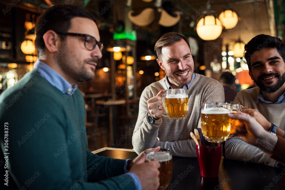 Happy group of friends drinking beer in pub