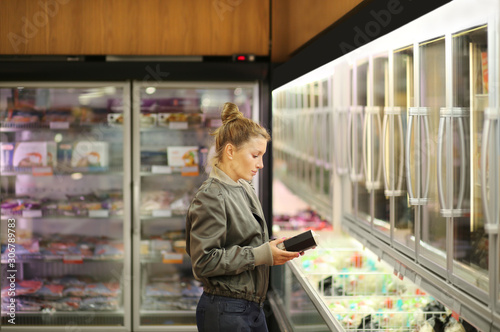 Woman choosing frozen food from a supermarket freezer 