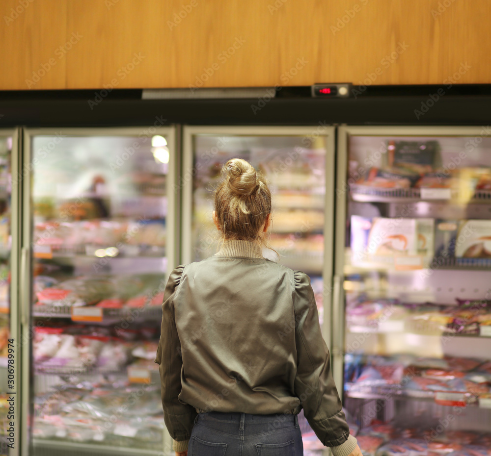 Woman choosing frozen food from a supermarket freezer Woman choosing frozen food from a supermarket freezer