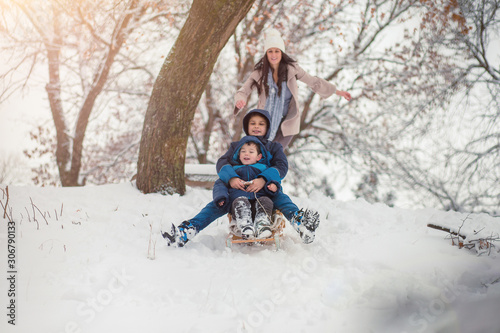 Young, beautiful mom and her cute little boy enyoing winter, sledding