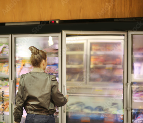 Woman choosing frozen food from a supermarket freezer 